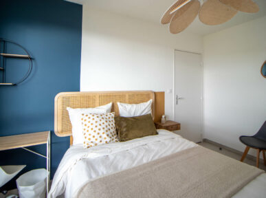 chambre à louer à Lyon (69) par Colivys, mur bleu, chaise noire, tête de lit en bois, porte blanche