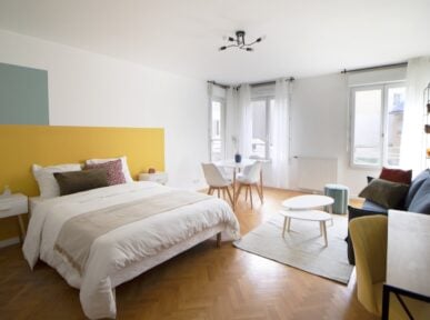 Chambre double à louer à Saint Denis (93) par Colivys avec un lit double, mur jaune et vert, parquet au sol