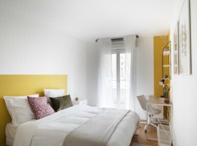 Chambre double à louer à Saint Denis (93) par Colivys tête de lit peinte en jaune, table de chevet blanche et bureau en bois