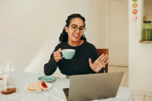 Femme en visio devant son ordinateur avec son café