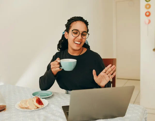 Femme en visio devant son ordinateur avec son café